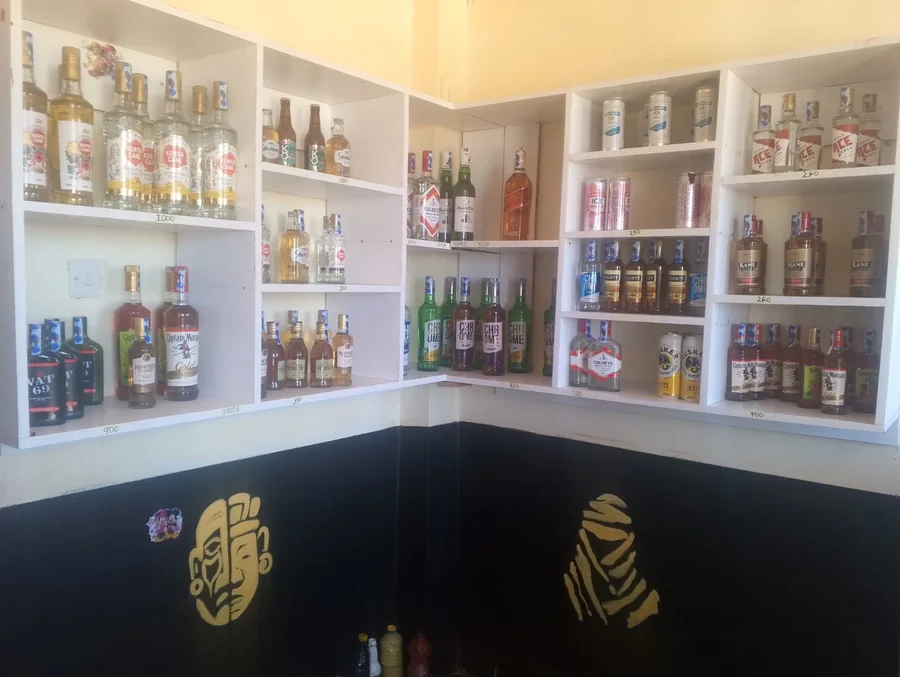Bottle shelves and the gold painted faces on the walls of AlCOOl in Kutus